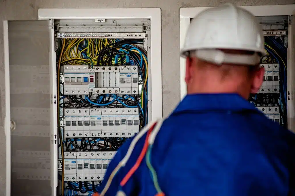 Electrician with a hard hat in front of an open electrical distribution board