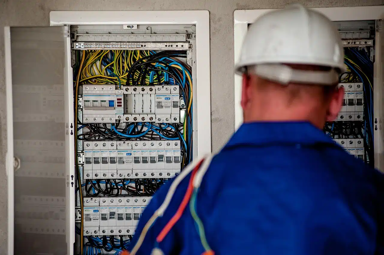 Electrician with a hard hat in front of an open electrical distribution board